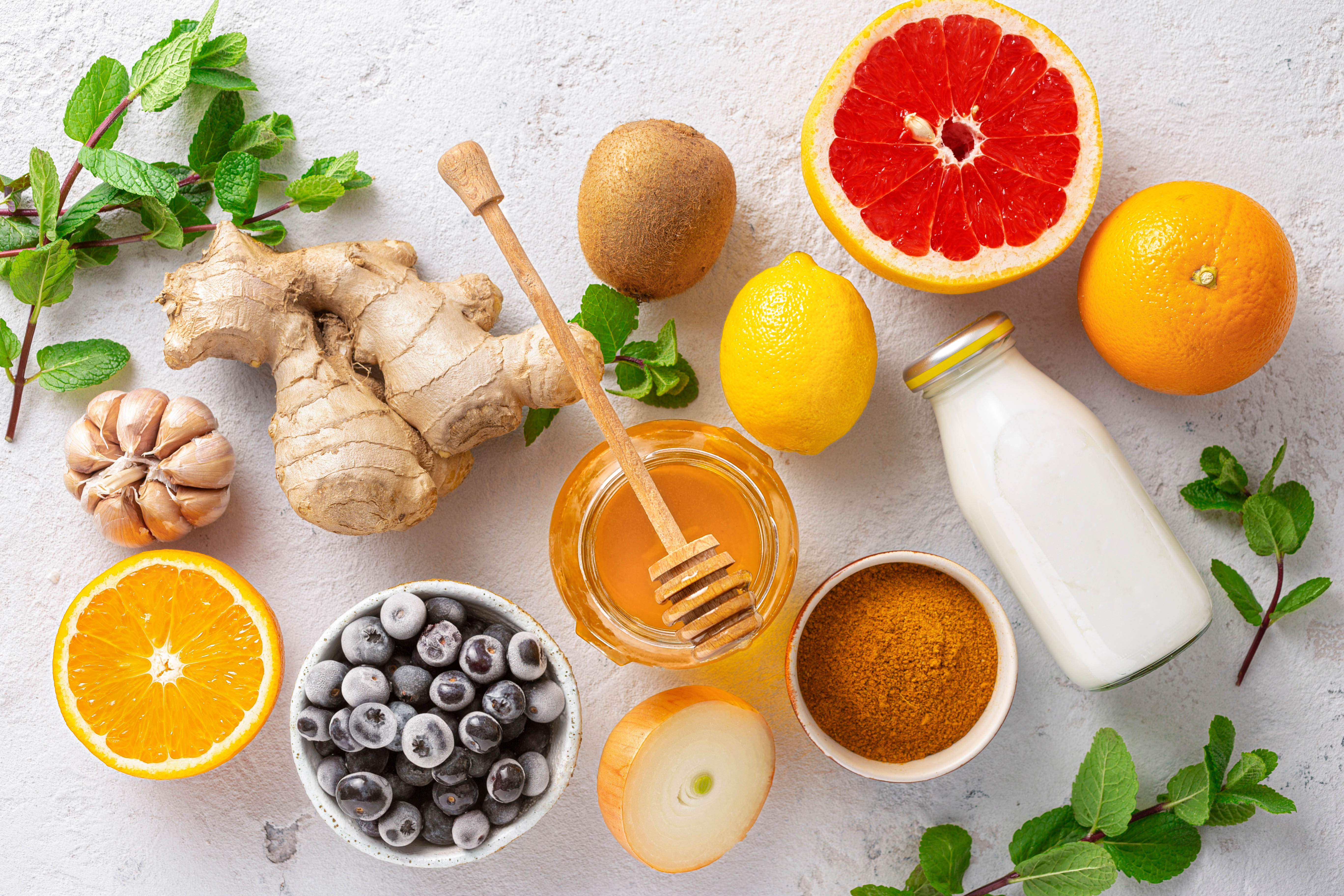 Immune boosting foods, including oranges, ginger, garlic, honey, kiwi, grapefruit, lemon, blueberries, onion, milk, and herbs Immune boosting foods, including oranges, ginger, garlic, honey, kiwi, grapefruit, lemon, blueberries, onion, milk, and herbs
